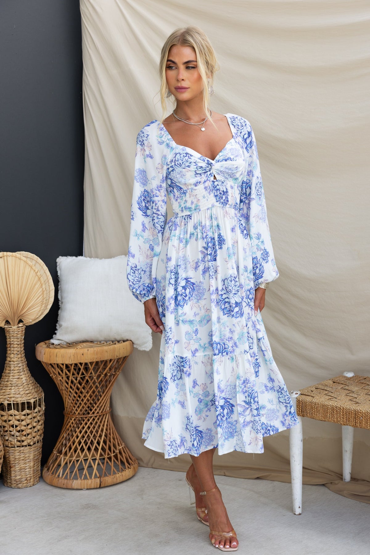 Floral print Celesta midi dress featuring elastic sleeves and pockets, styled with sandals in a chic indoor setting.
