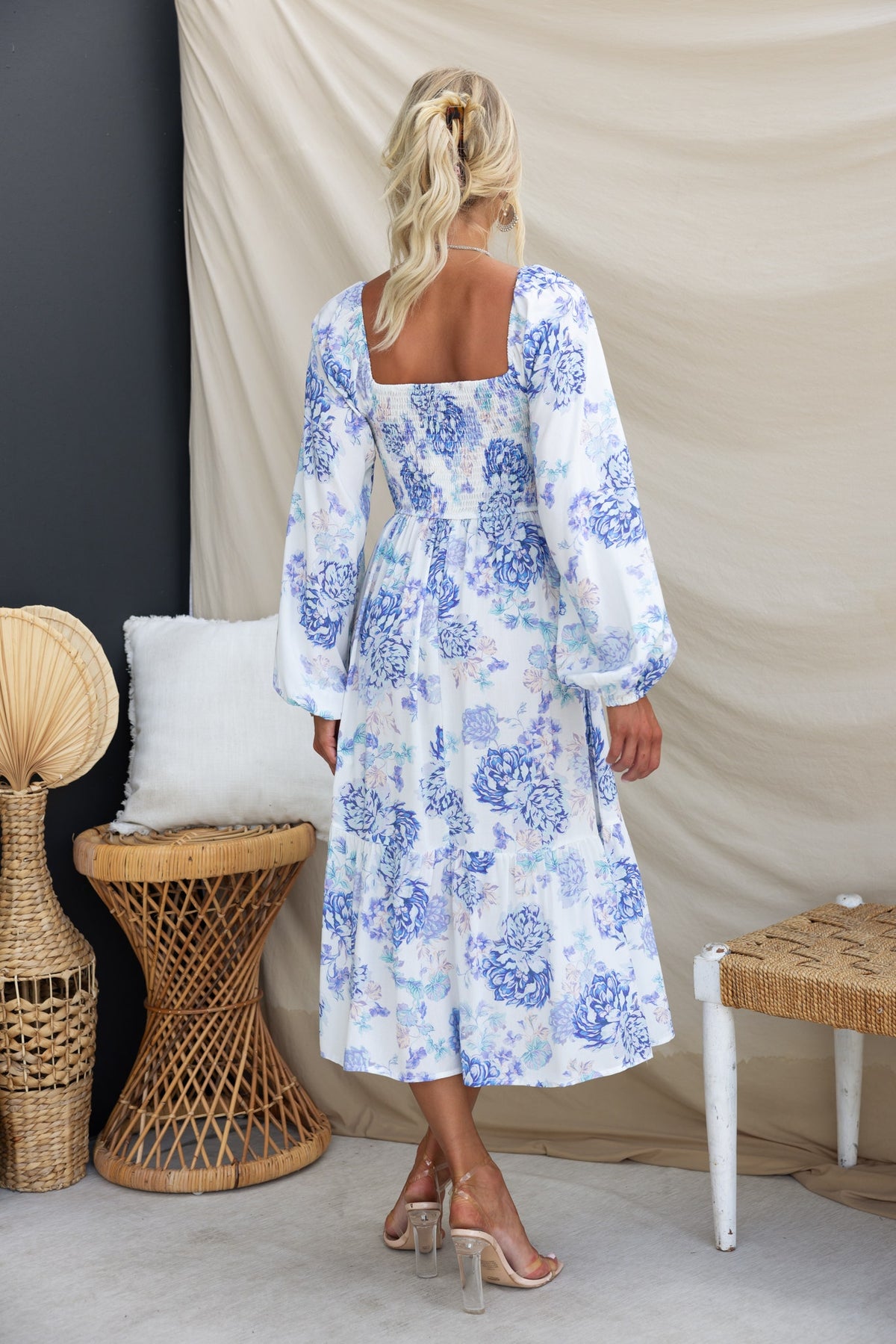 Back view of a floral print Celesta Midi Dress with elastic sleeves and twist detail, styled with soft furnishings.
