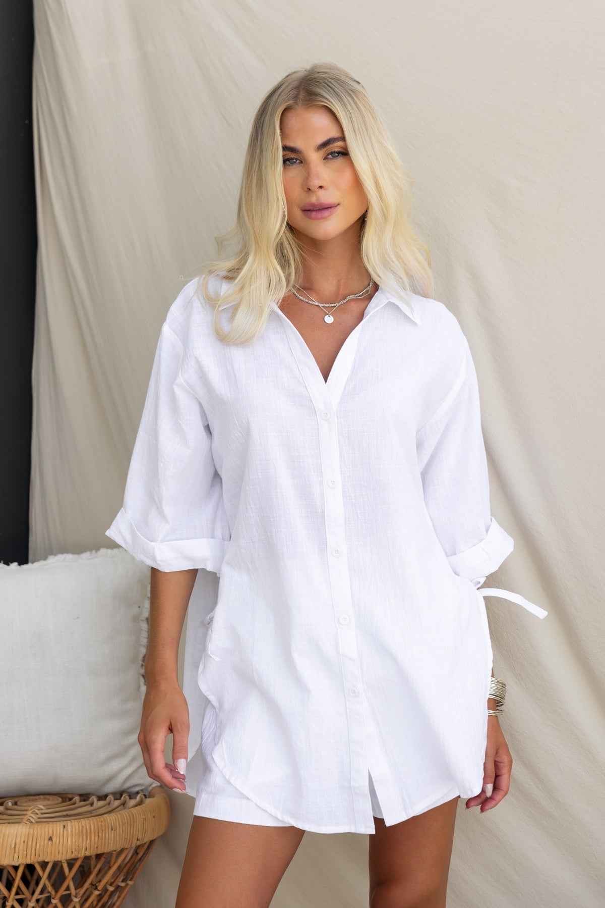 Model wearing the Oceania Shirt, a relaxed white button-up with rolled cuffs and side tie details.