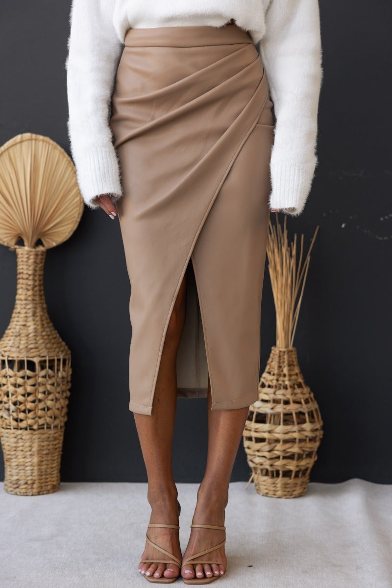 Qorinda Midi Skirt in faux leather, featuring asymmetrical hemline and invisible zip, styled with a cozy sweater.