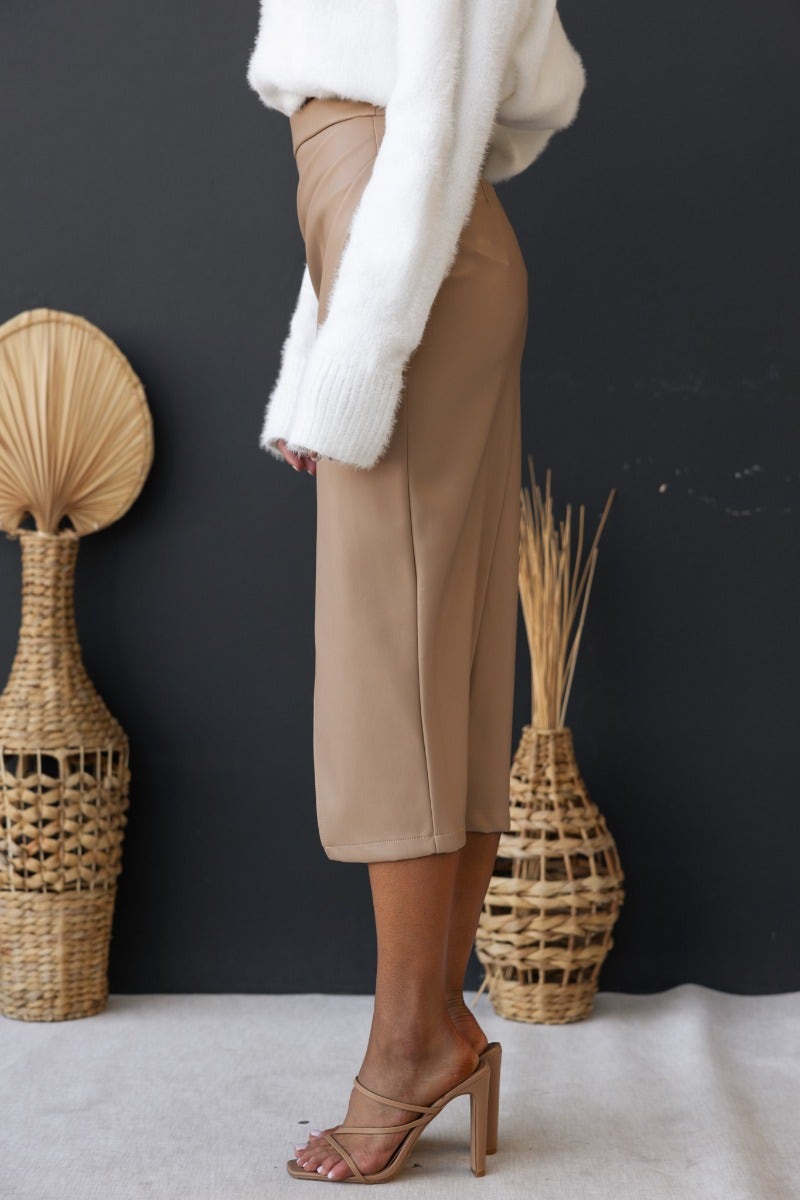 Model wearing Qorinda midi skirt in faux leather with asymmetrical hemline and invisible zip, styled with a cozy sweater.