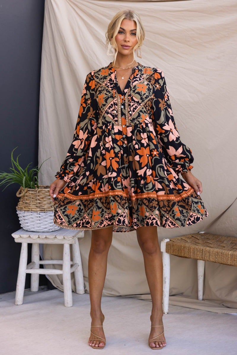Stellan dress featuring a black multi-color print, V-neckline, button-up front, and elastic cuffs at sleeves.