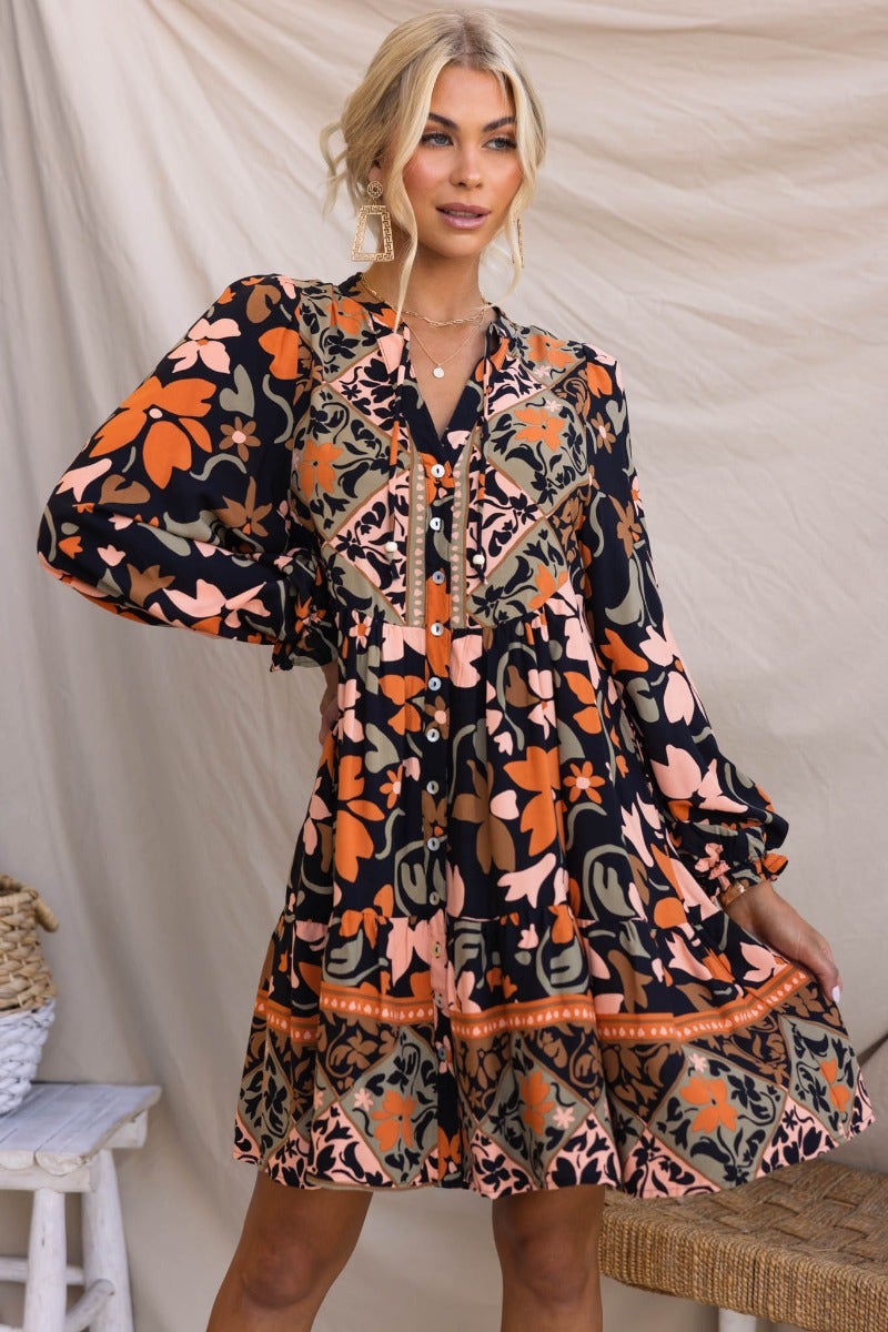 Stellan Dress: Black multi-color print dress with V-neckline, button-up front, and elastic cuffed sleeves.