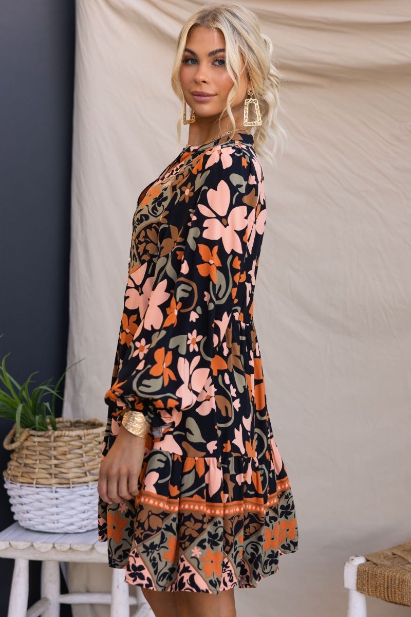 Stellan Dress: Black multi-color floral print dress with V-neckline, button-up front, pockets, and elastic cuffs.