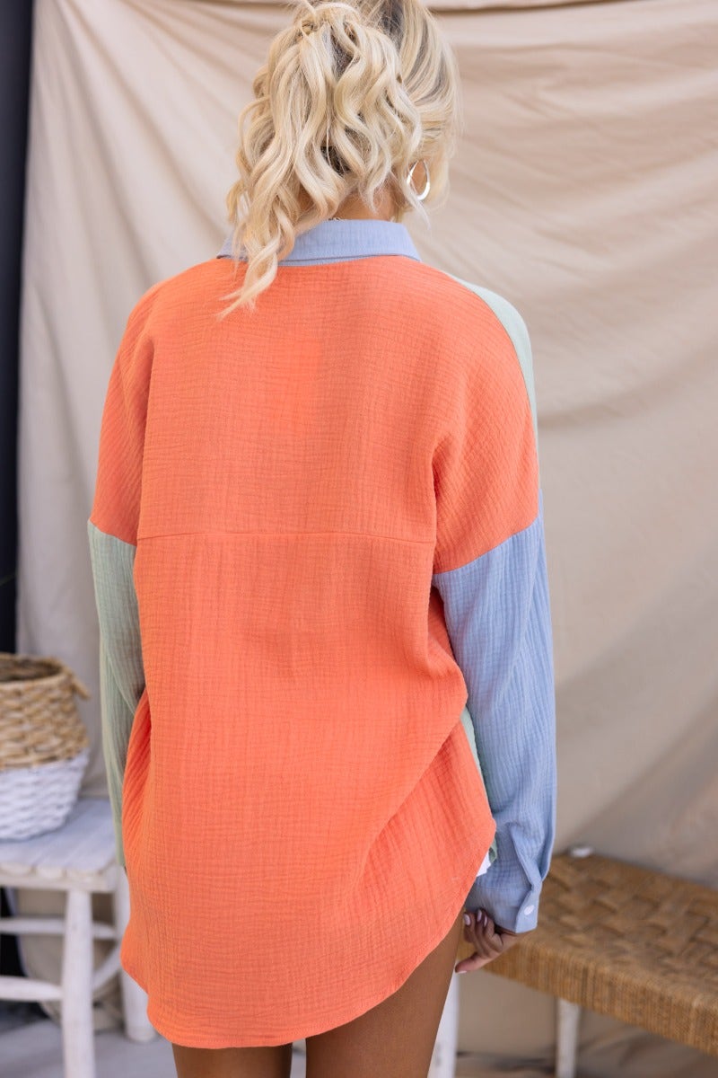 Back view of Atticus Top, an oversized, lightweight cotton button-up shirt in orange and blue, perfect for casual wear.