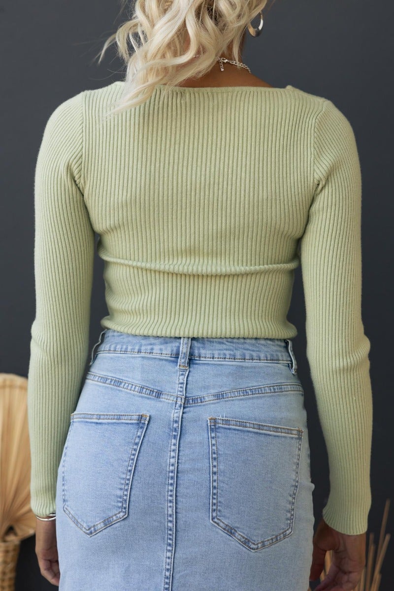 Back view of woman wearing Daia Top in ribbed knit, showcasing asymmetrical neckline and stylish fit.
