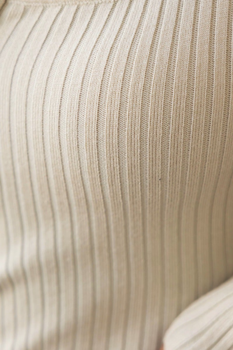 Close-up of ribbed knit material in a beige bodysuit, showcasing its texture and stretch.