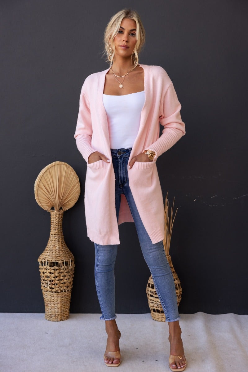 Hailey Cardigan in soft pink, ribbed knit with longline fit and front pockets, styled with skinny jeans.