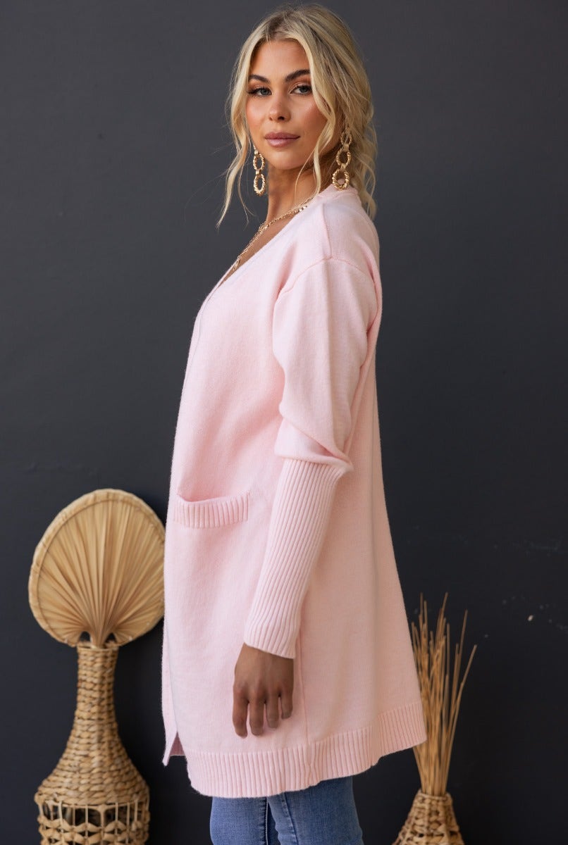 Hailey Cardigan in soft pink, longline ribbed knit with front pockets, worn casually with denim jeans.