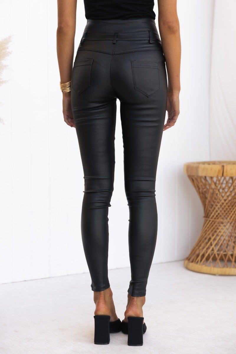Back view of black faux leather Leni Pants with mid-high waist, showcasing pockets and skinny fit.