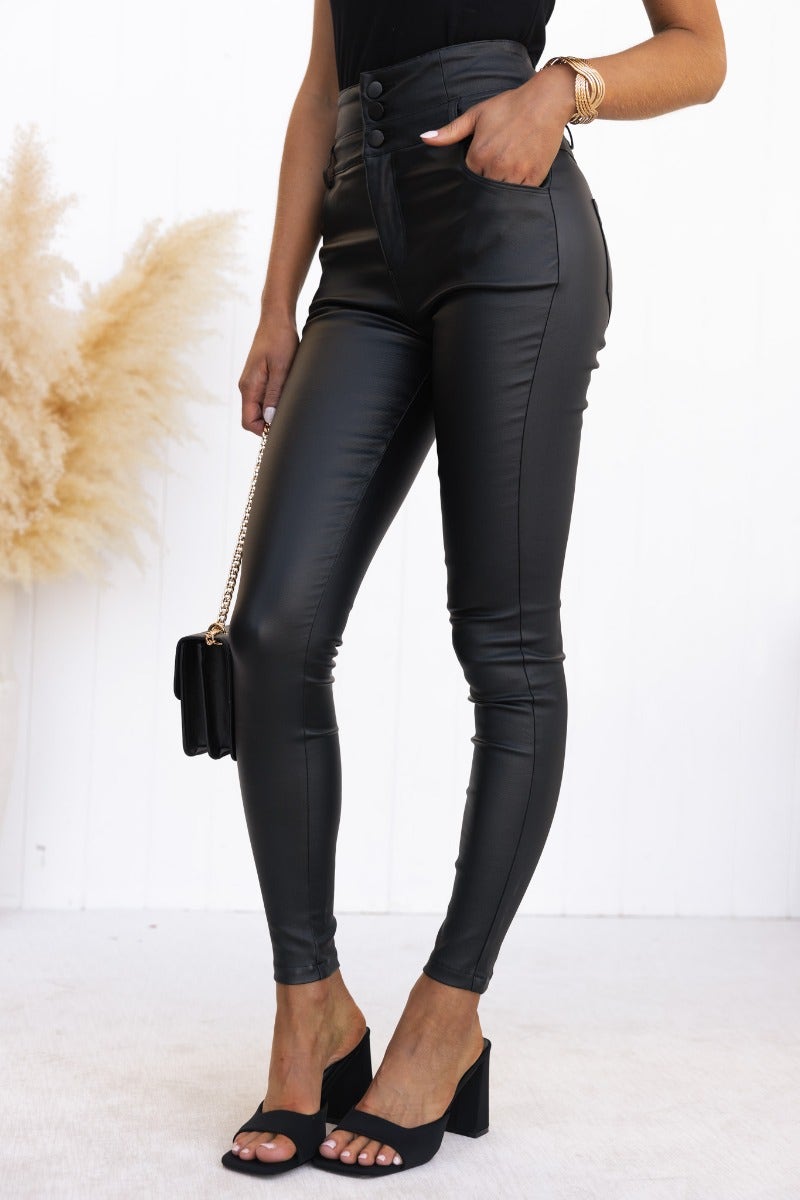 Black faux leather Leni pants with mid-high waist fit and pockets, showcasing a modern skinny silhouette.