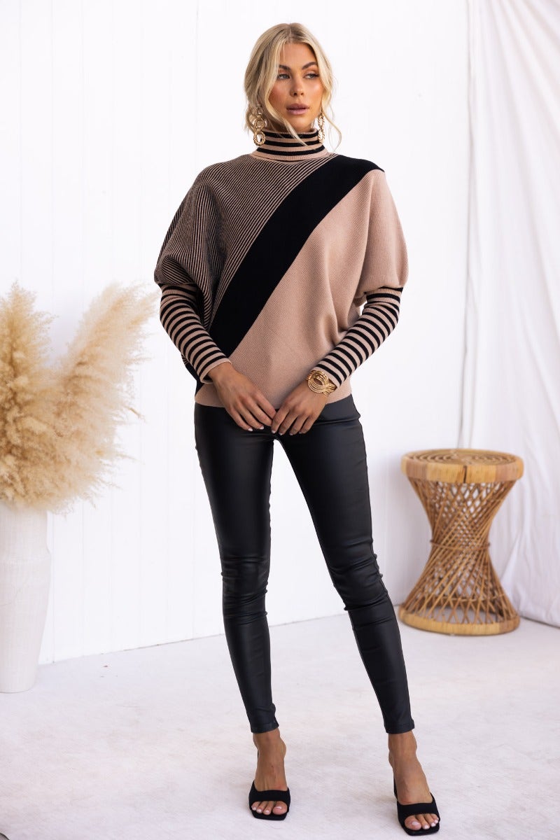 Model wearing Reality Check Jumper in ribbed knit, batwing sleeves, and turtle neckline, paired with faux leather pants.