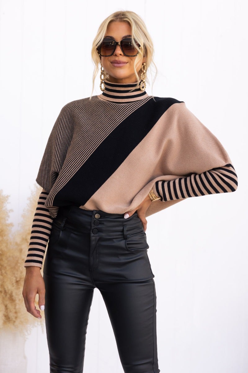 Reality Check Jumper featuring ribbed knit, batwing sleeves, and turtle neckline, styled with high-waisted black pants.
