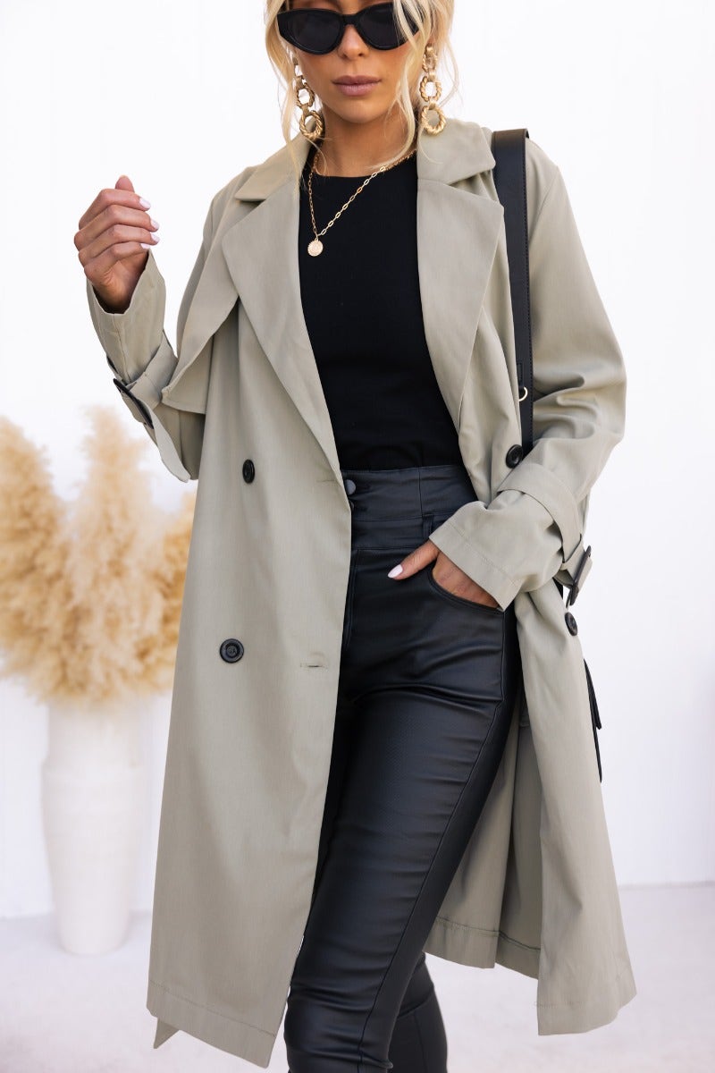 Stylish woman wearing a Cheyla trench coat with button closure and removable belt, paired with black pants and sunglasses.
