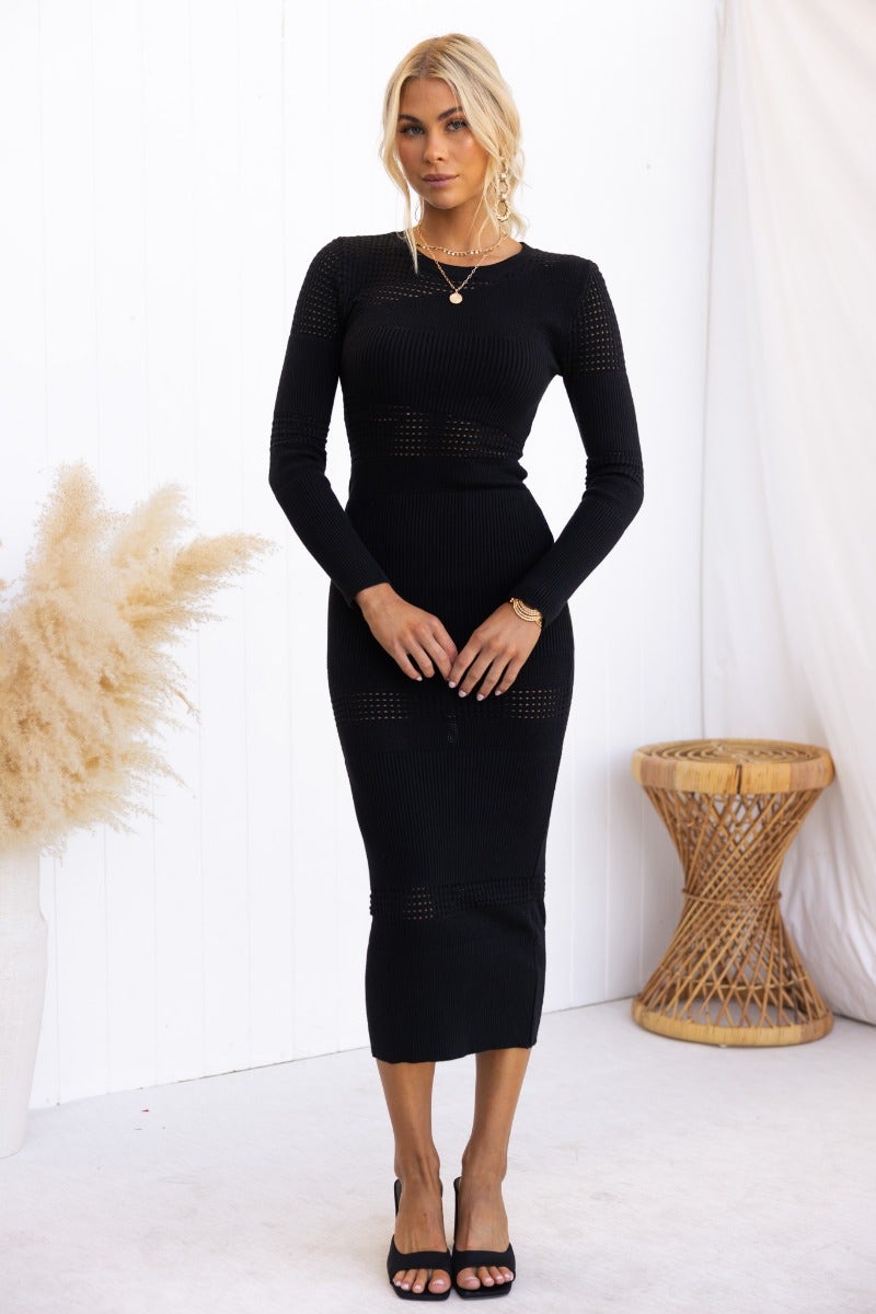Black ribbed knit midi dress with open weave detailing, styled on a model. Perfect for casual or evening wear.
