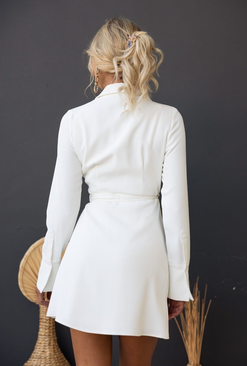 Back view of a woman in a white Valeria Wrap Dress with collar and fabric tie, showcasing a stylish and elegant fit.