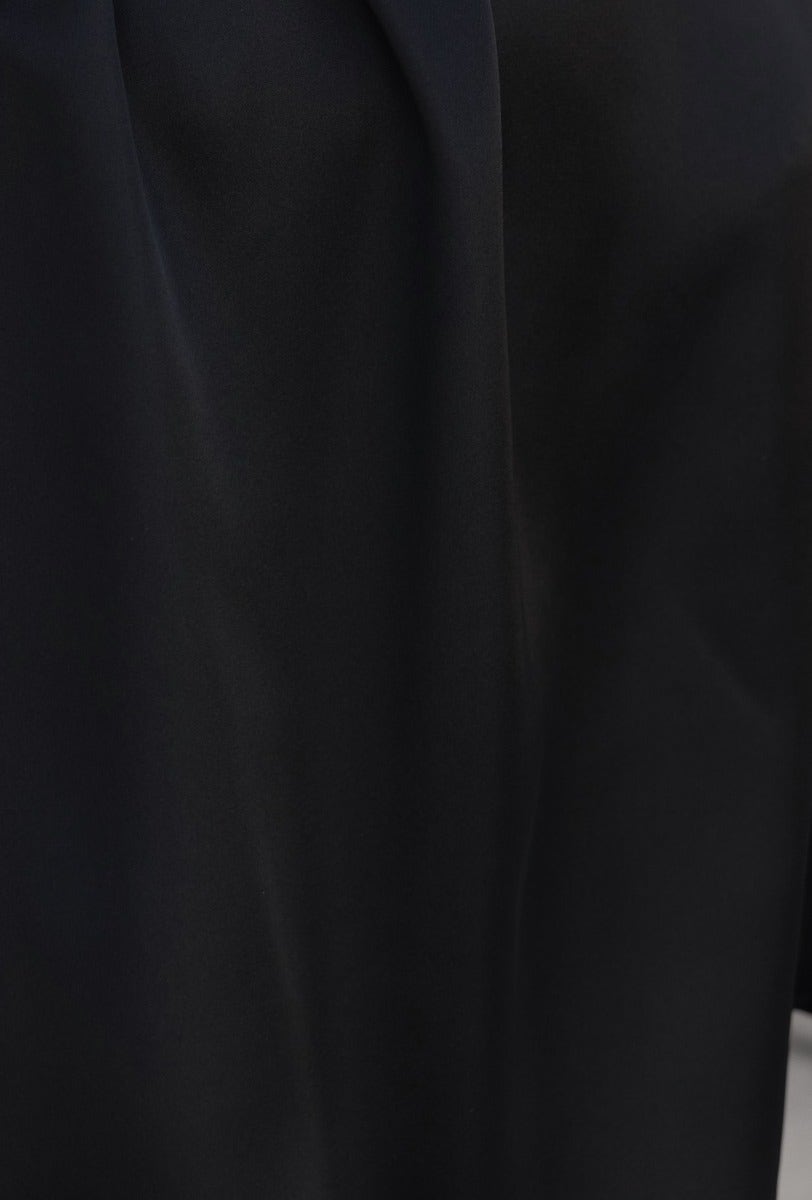 Close-up of black satin fabric showcasing texture of Charli Dress with smooth finish and elegant design details.