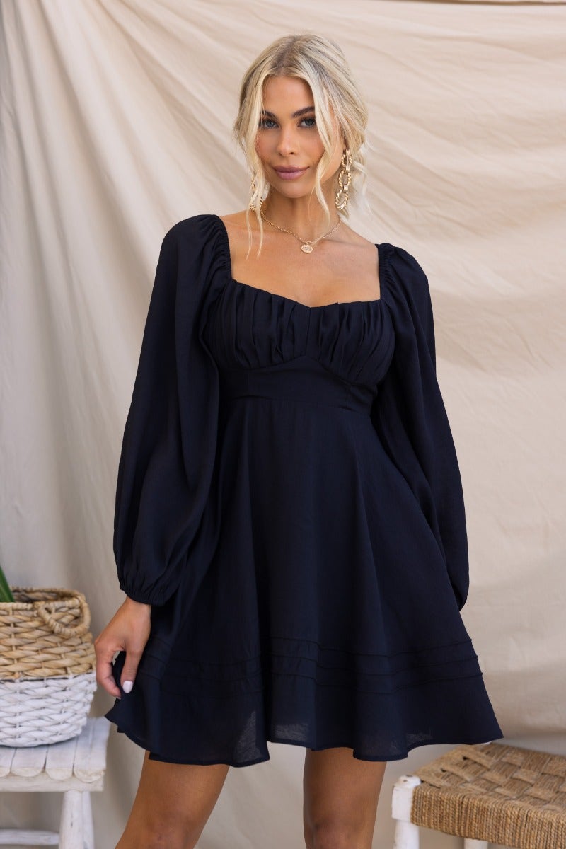 Model wearing a black Amos dress with a sweetheart neckline, puff sleeves, lined design, and an invisible zip at the back.