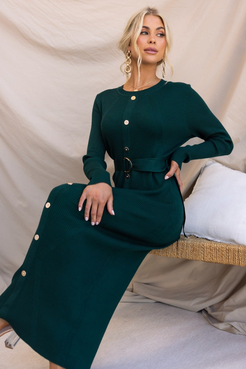 Woman in dark green ribbed Nicola maxi dress with round neckline and faux button-up front, styled with removable fabric belt.