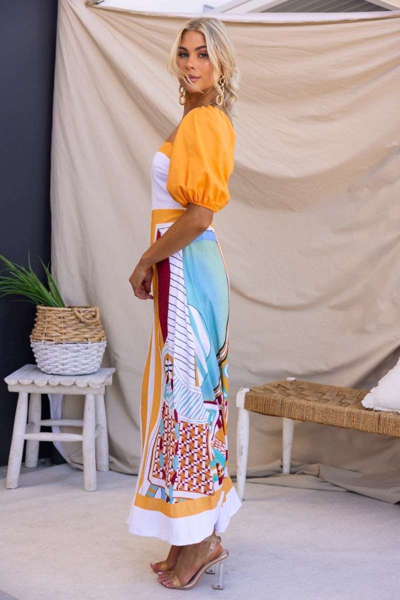 Model wearing a multi-colour Turner Maxi Dress with square neckline and elastic sleeves, showcasing vibrant patterns.
