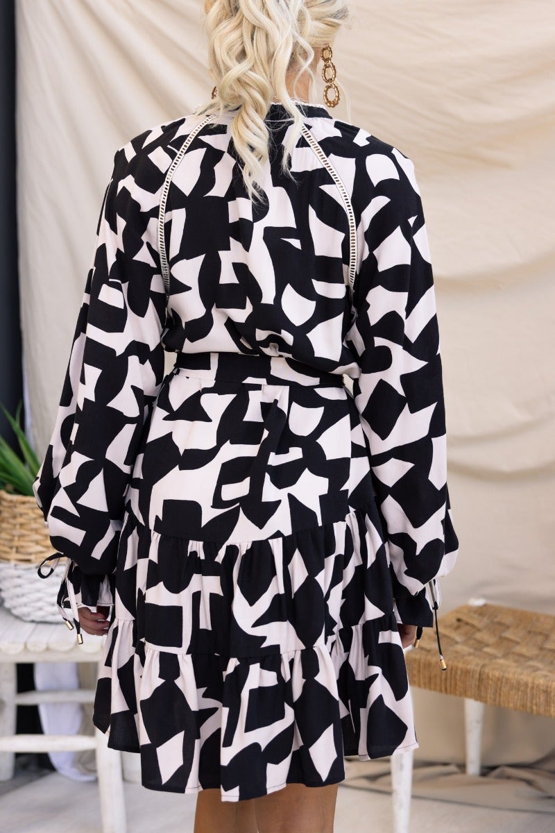 Back view of Hasley Dress featuring black and white abstract print, elastic cuffs, and removable belt.