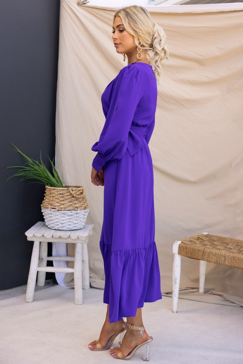 Model wearing a purple Alizzie Midi Dress with a V-neckline and puff sleeves, styled with a removable belt.