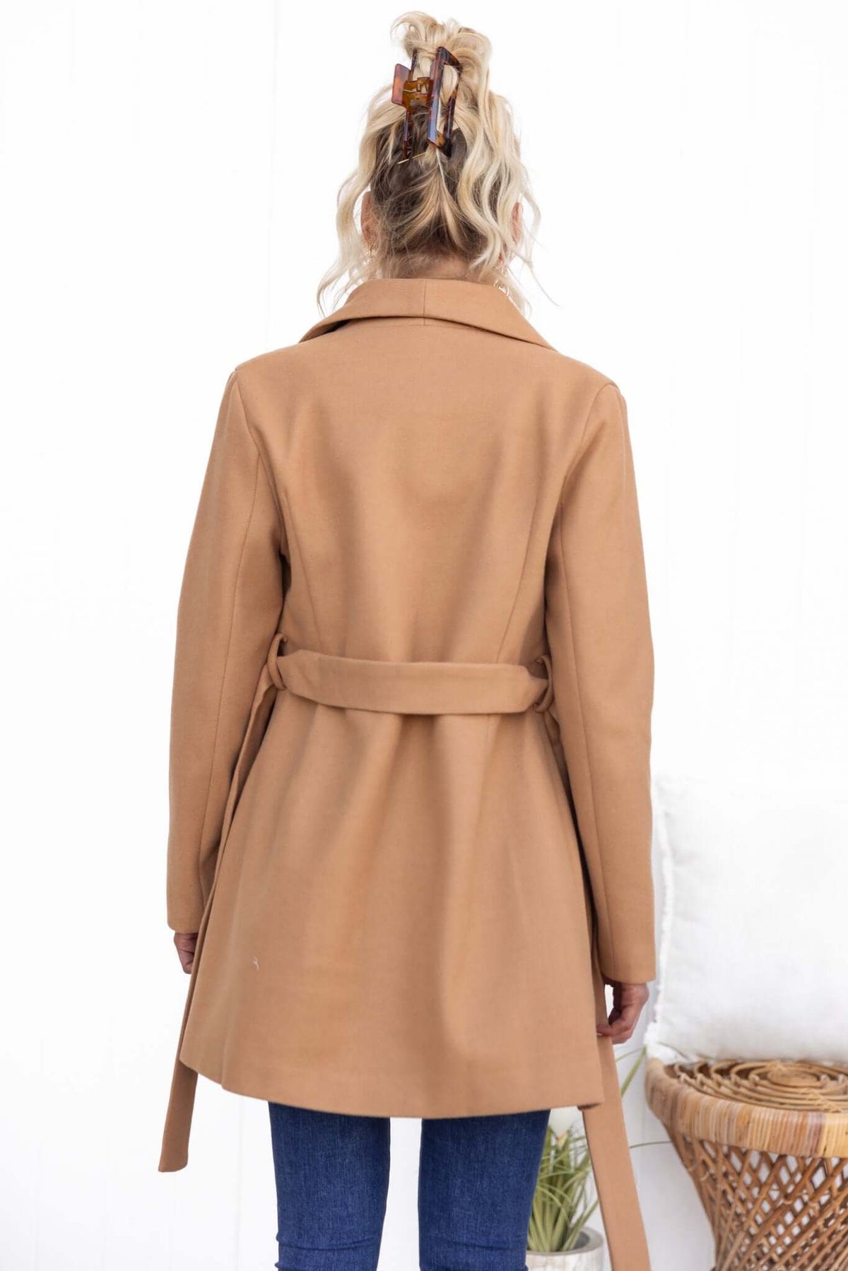 Back view of a woman wearing a stylish tan jean coat with a tied belt, ideal for casual and chic outfits.