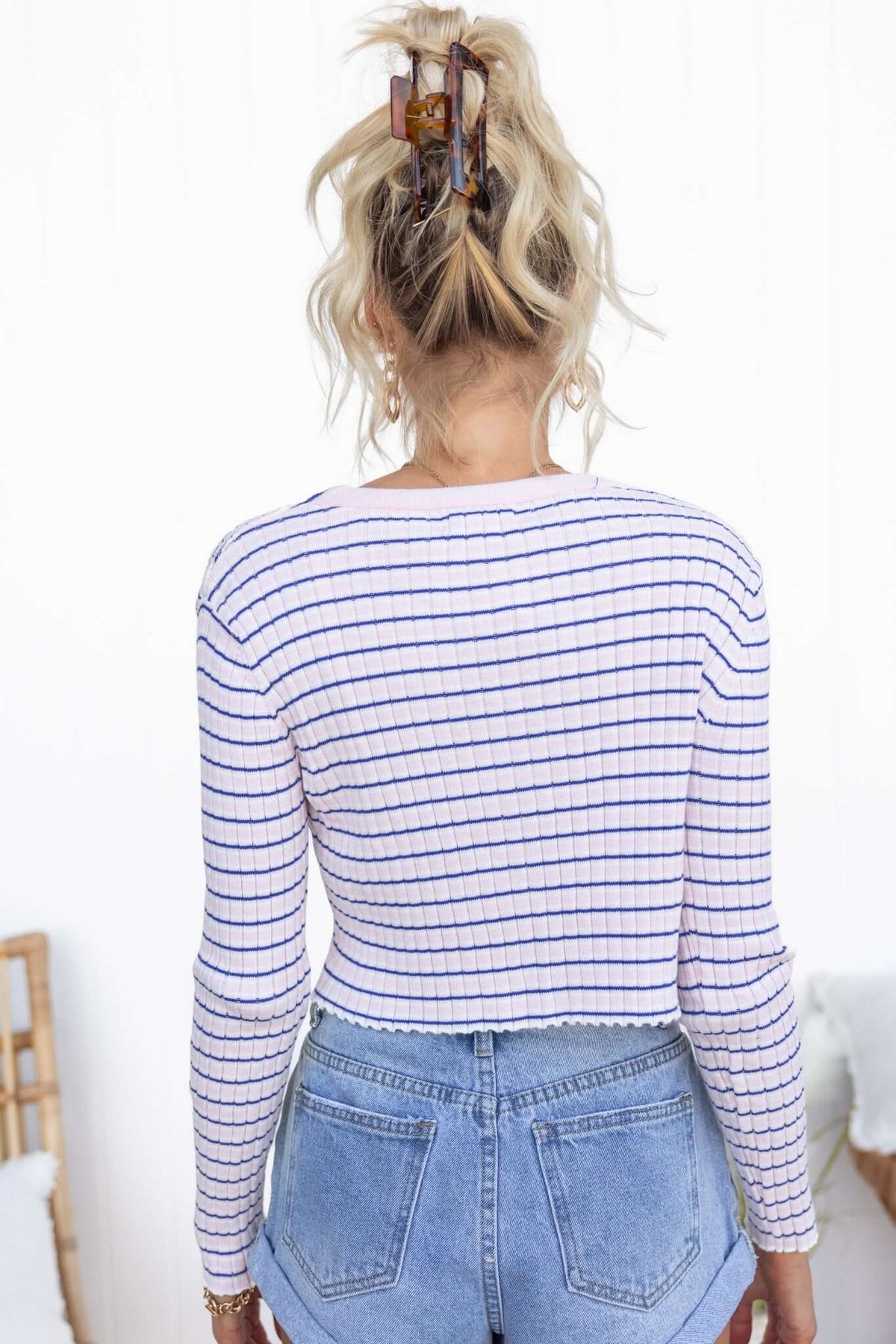 Back view of a woman wearing a striped Evan Top with a V-neckline and ribbed knit material paired with high-waisted shorts.