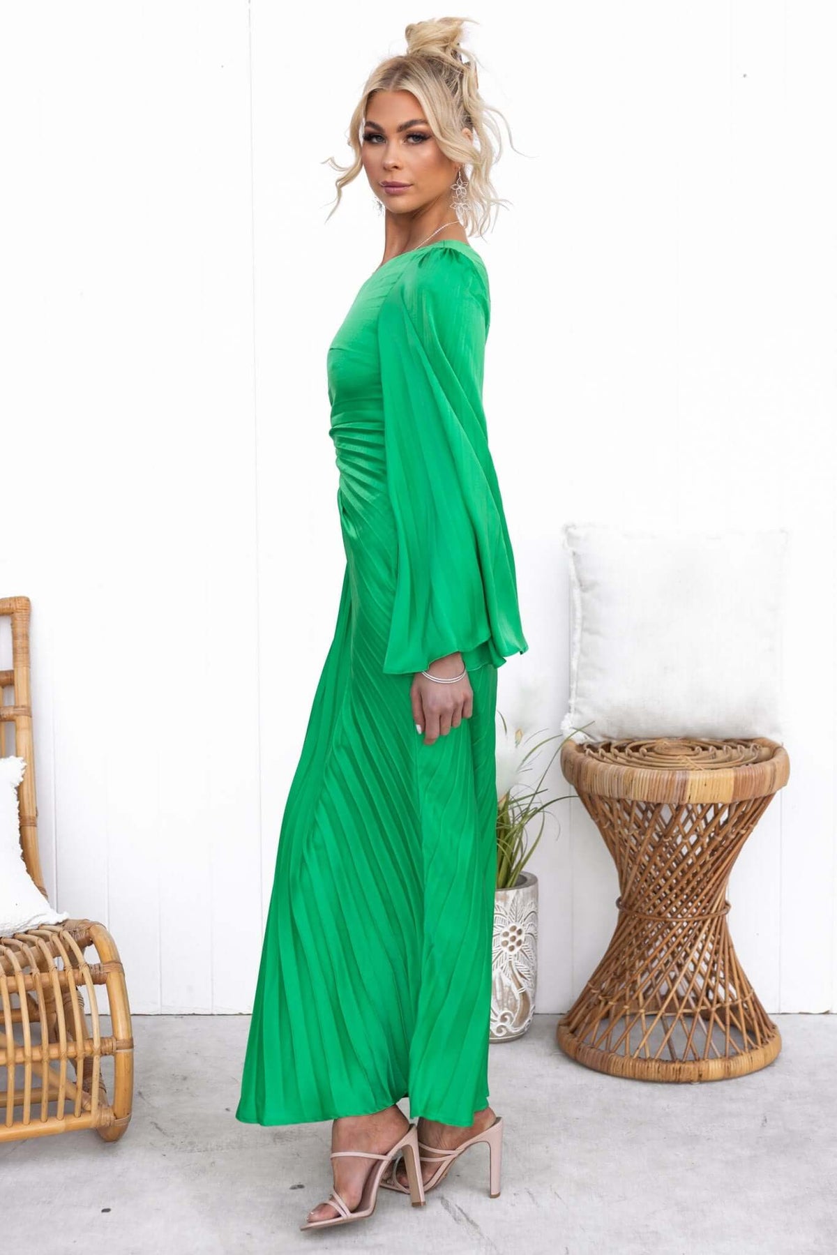 Model wearing a green pleated maxi dress with one-shoulder style and cut-out waist on a white background.