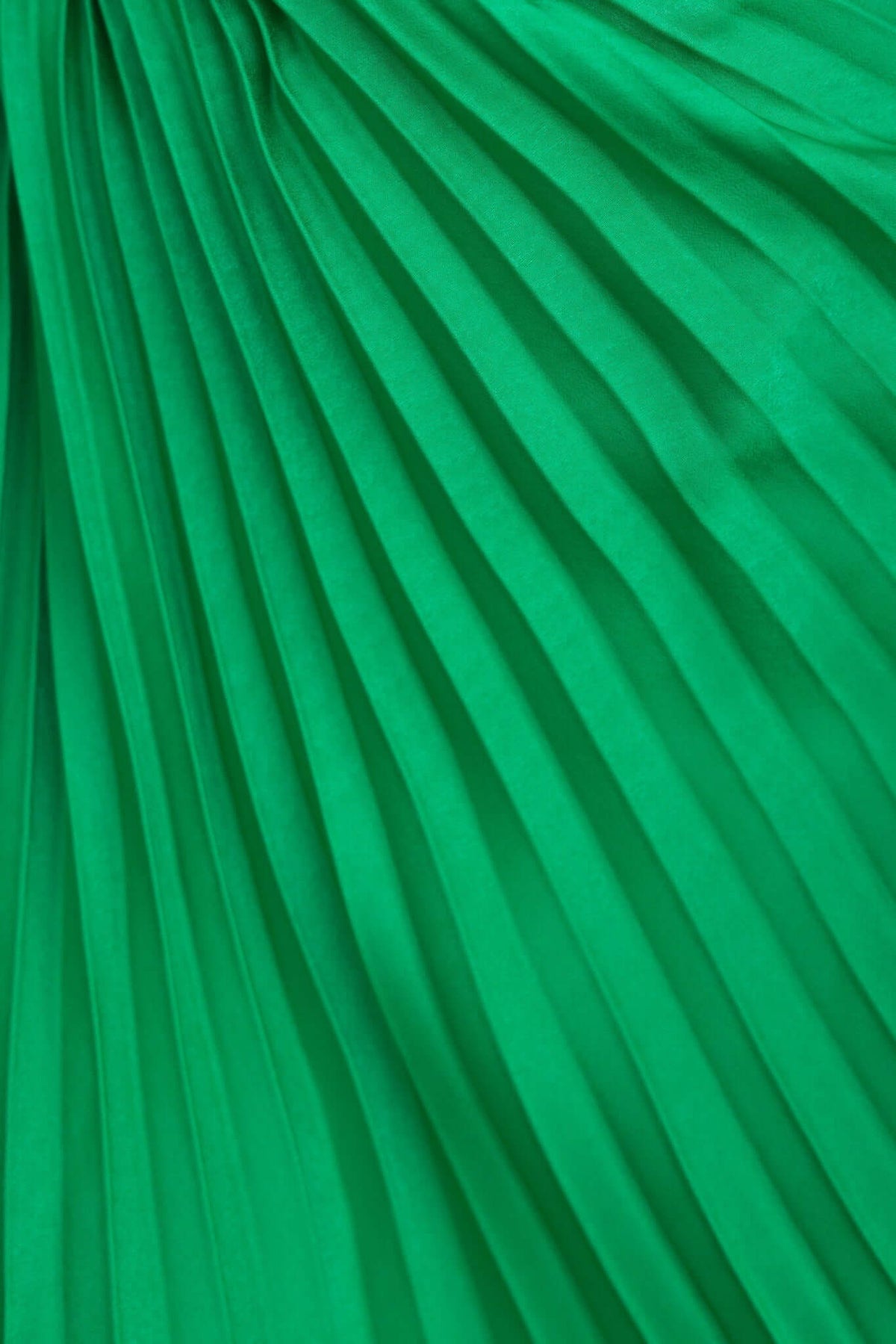 Close-up of pleated green fabric showcasing the texture and flow of the Regal Maxi Dress.