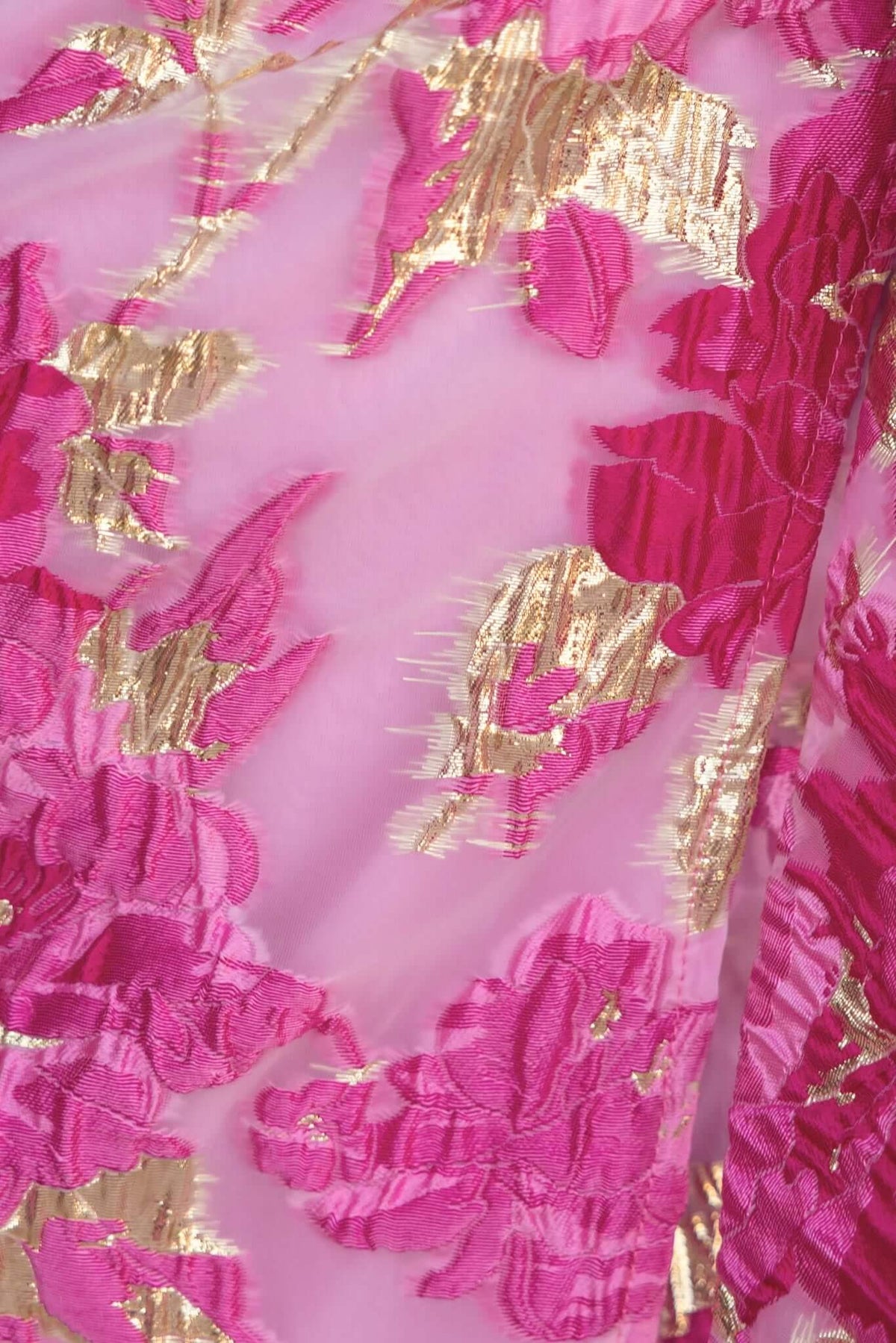 Close-up of pink and gold floral textured fabric, showcasing the detailed design ideal for a formal dress.