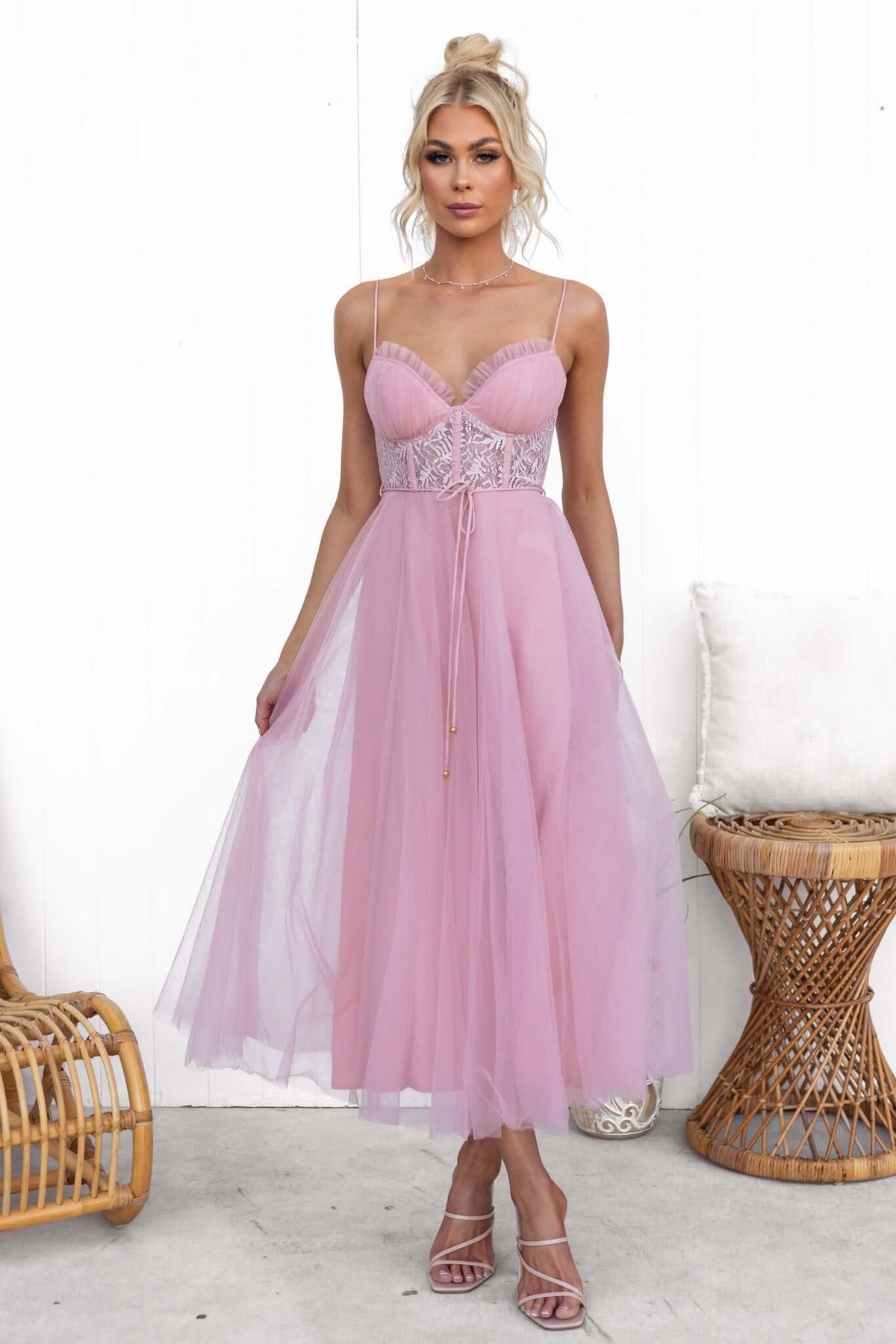 Tulle maxi dress in blush pink with adjustable straps and lace detail, styled elegantly for a chic look.