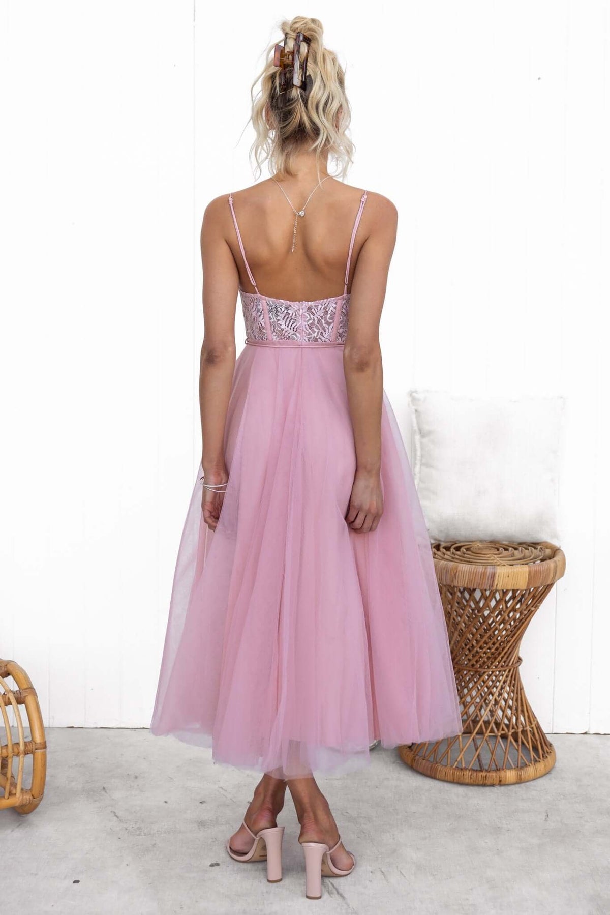 Back view of a model in a pink tulle maxi dress with lace detail and adjustable straps, showcasing a chic and elegant look.