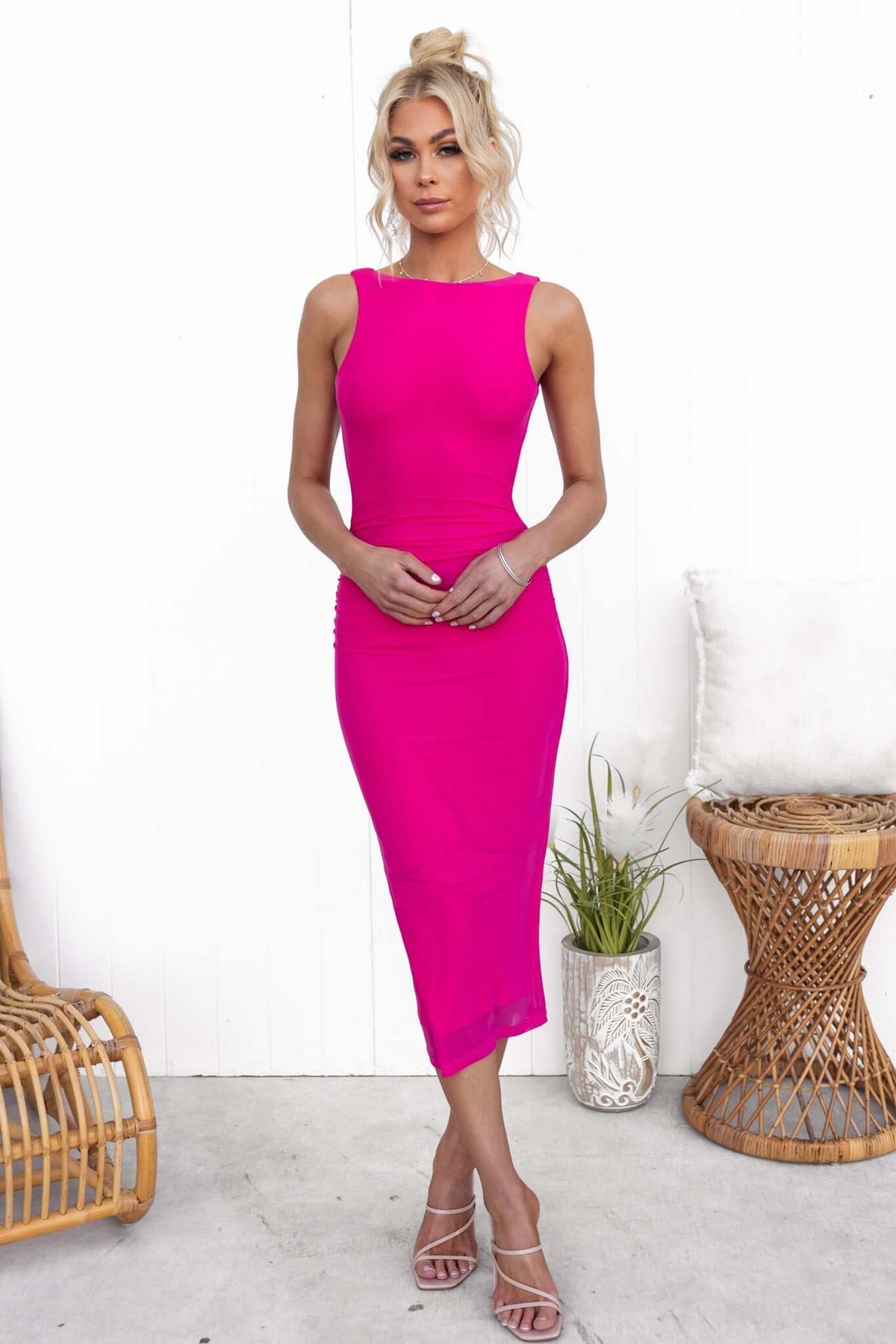 Aletta Midi Dress in vibrant pink, featuring a high neckline, open back, and stretch mesh material, styled with elegant accessories.
