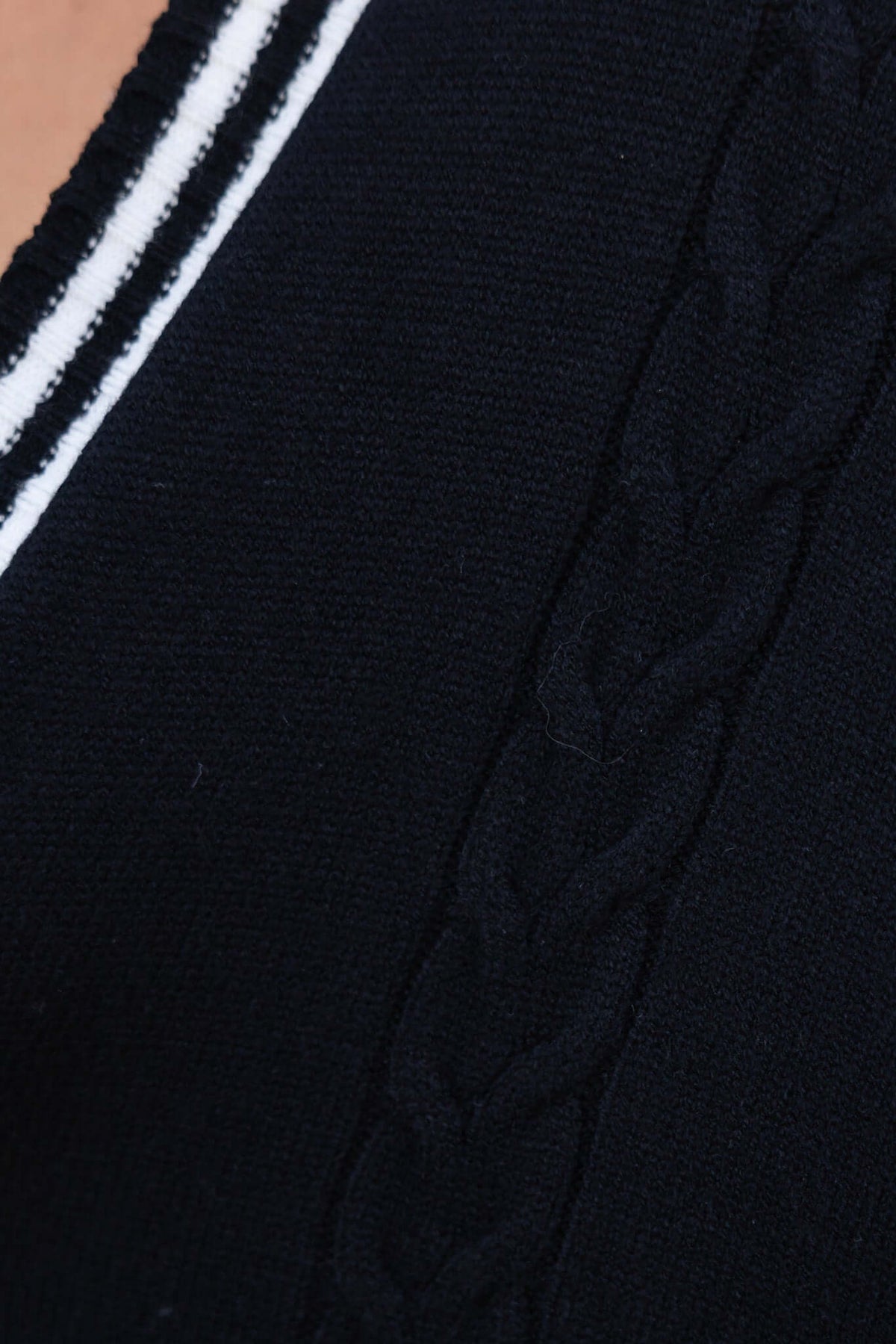 Close-up of Gritti cardigan showing black knit fabric with braided texture and white stripes.