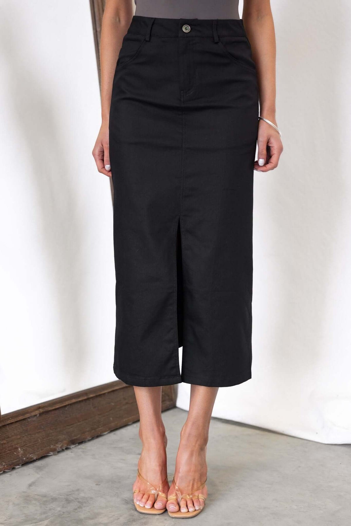 Burbank Midi Skirt in black with a mid-high waist, front split, and pockets, styled with a casual top.
