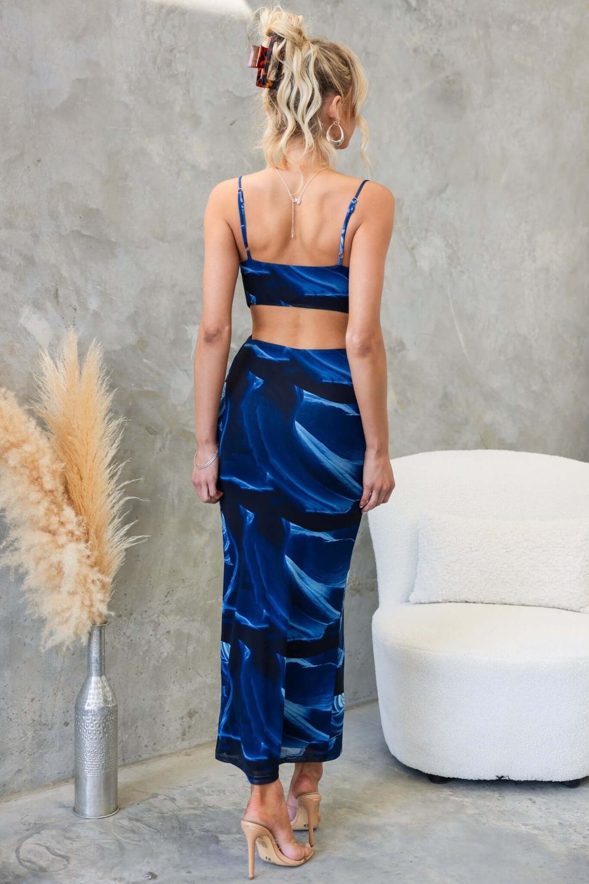 Model wearing Kalena Maxi Dress with adjustable straps and cowl neckline, showcasing a blue abstract design and back cut-out.