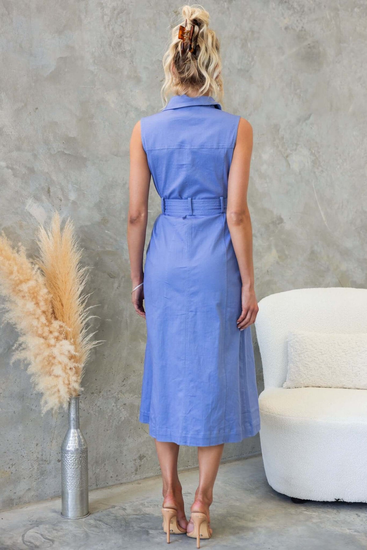 Back view of a Kinston Denim Midi Dress in light blue with a collar and belt detail, styled in a modern setting.