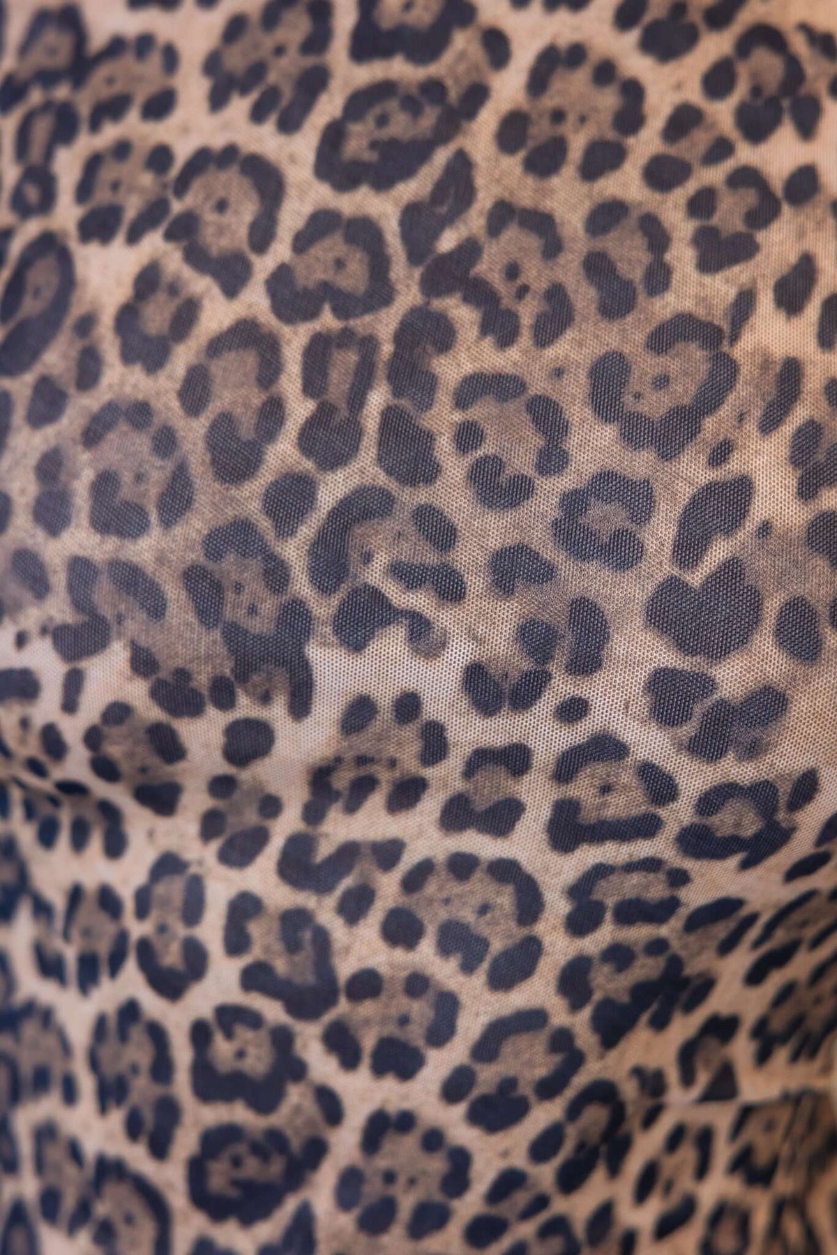 Close-up of leopard print fabric showcasing bold patterns on a lightweight mesh material.