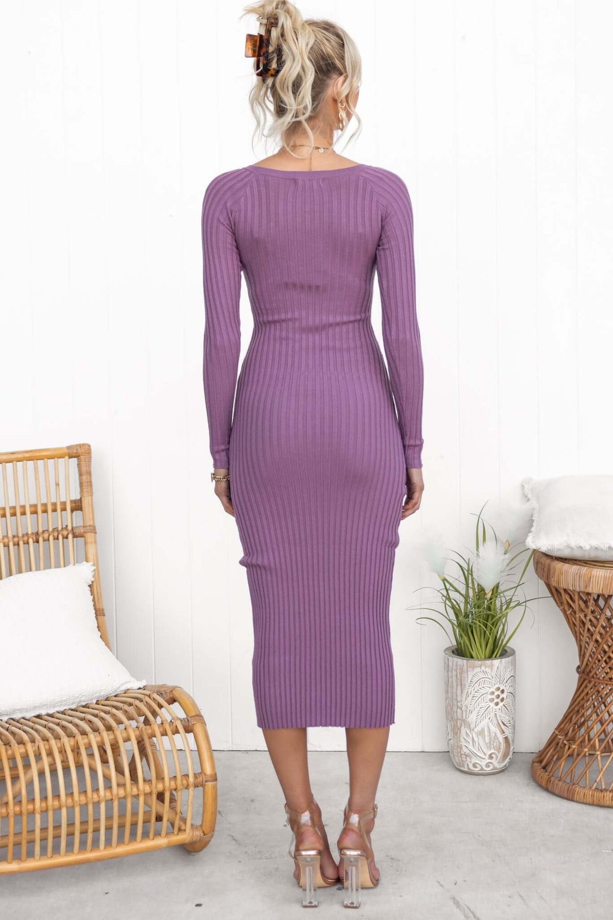Back view of a woman in a purple ribbed midi dress styled with a casual hairstyle and silver heels.