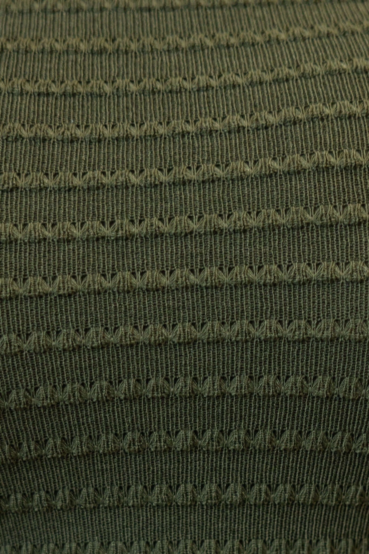 Textured green fabric close-up showcasing intricate knit patterns for a stylish maxi dress.