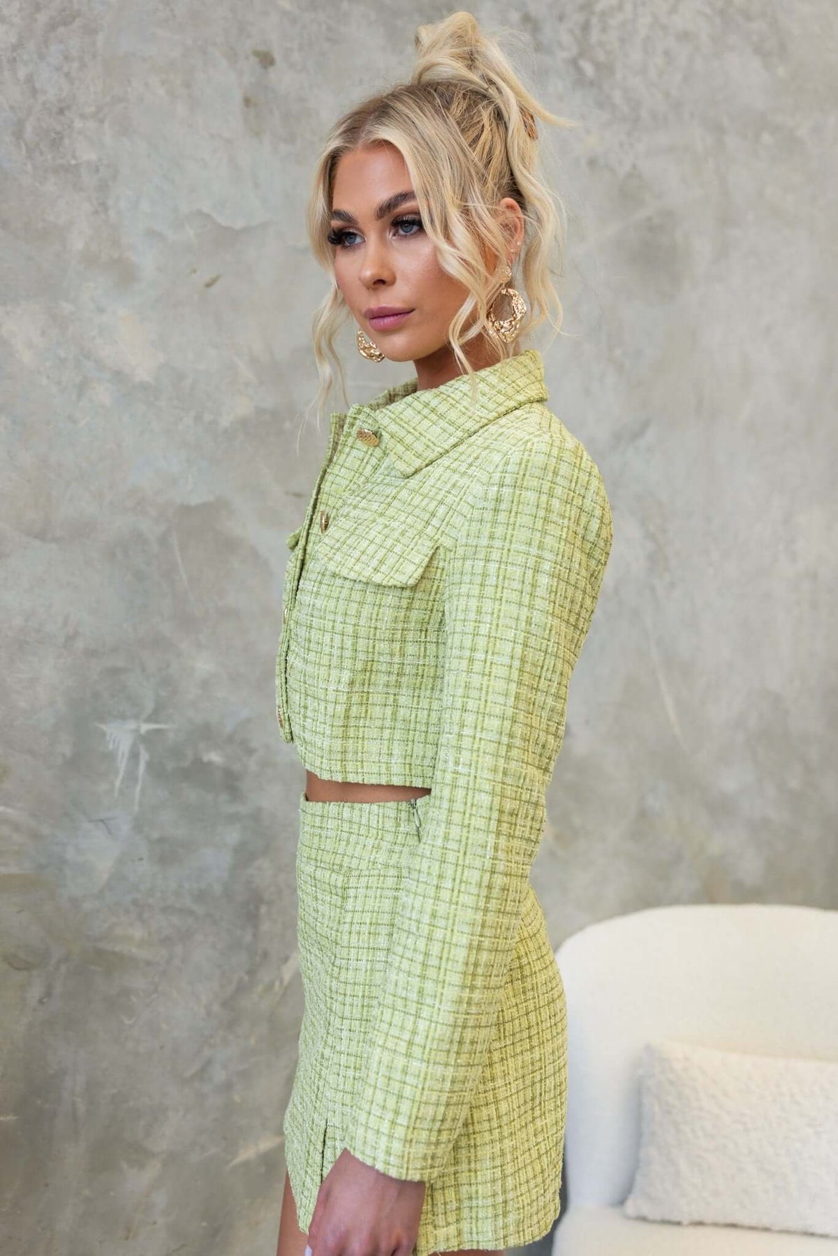 Model wearing the Sophia Coat, a cropped tweed coat in green with faux pockets and button-up front, styled elegantly.