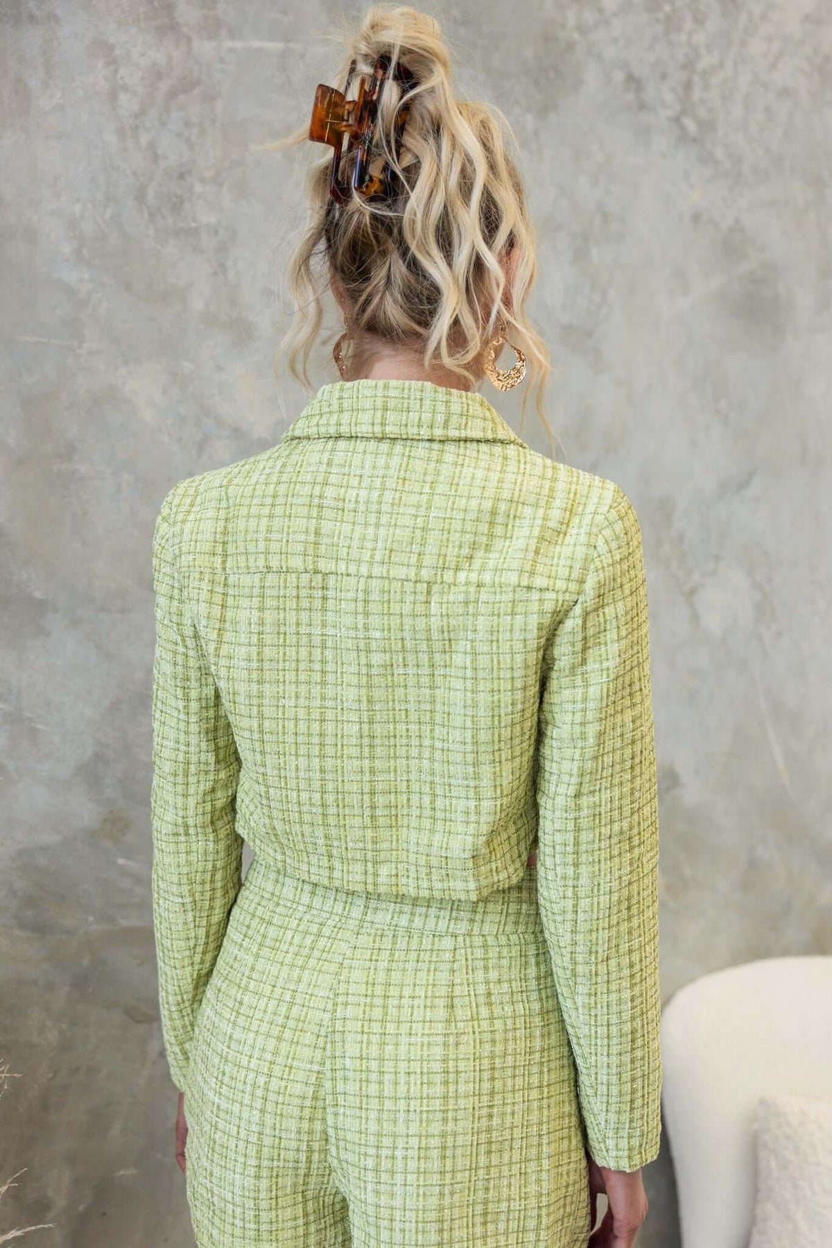 Back view of a woman wearing a green tweed Sophia Coat with a collar and faux pockets, styled with hair accessories.