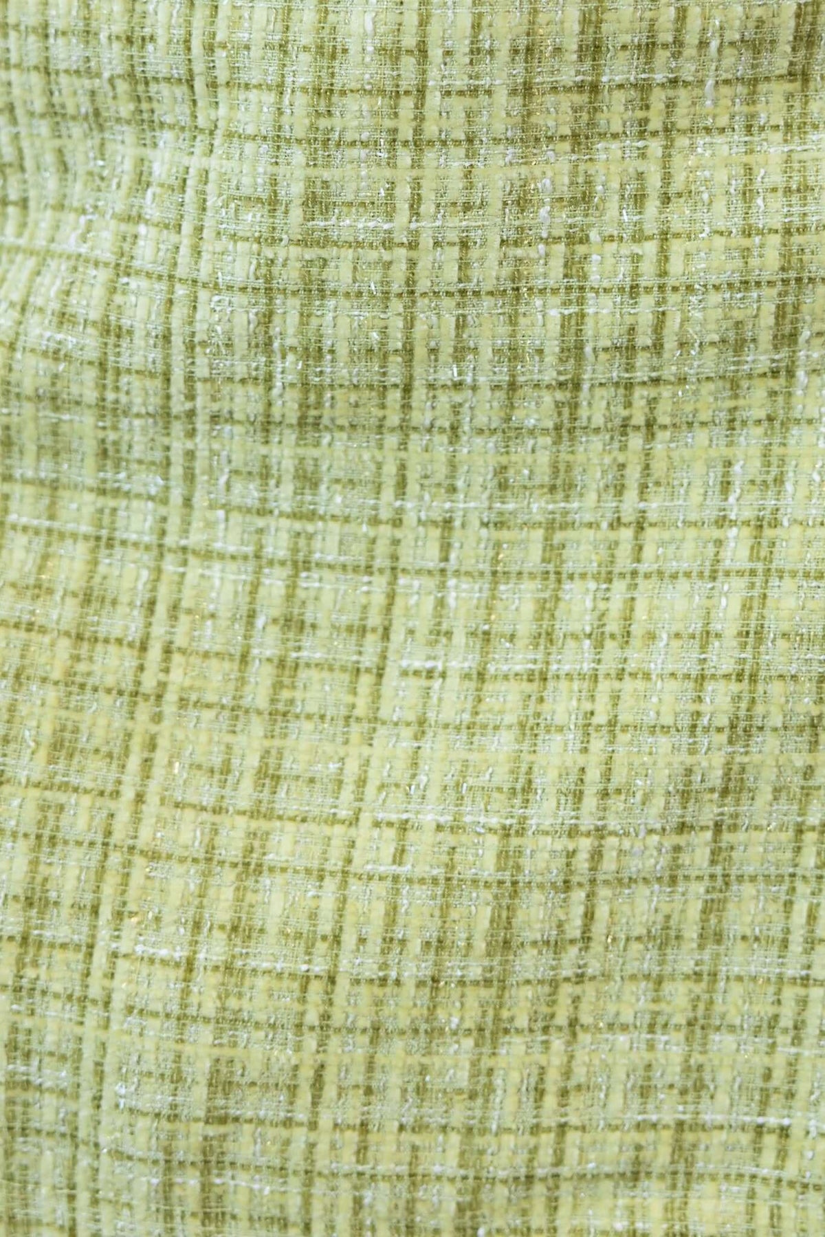 Close-up of textured fabric in light green tweed, showcasing a plaid pattern suitable for a chic coat design.