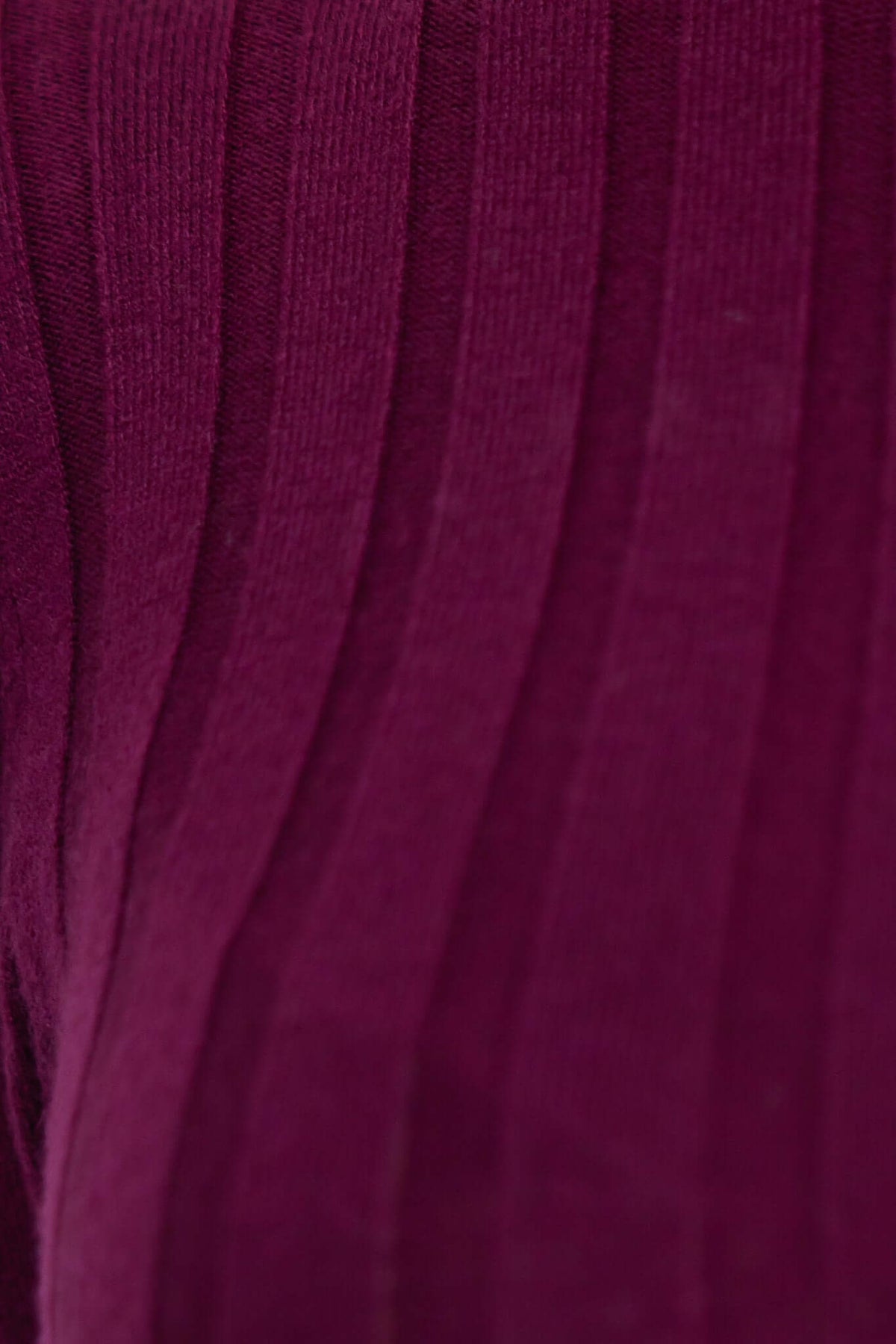 Close-up of ribbed knit fabric in rich burgundy color, showcasing texture and stretch of the material.