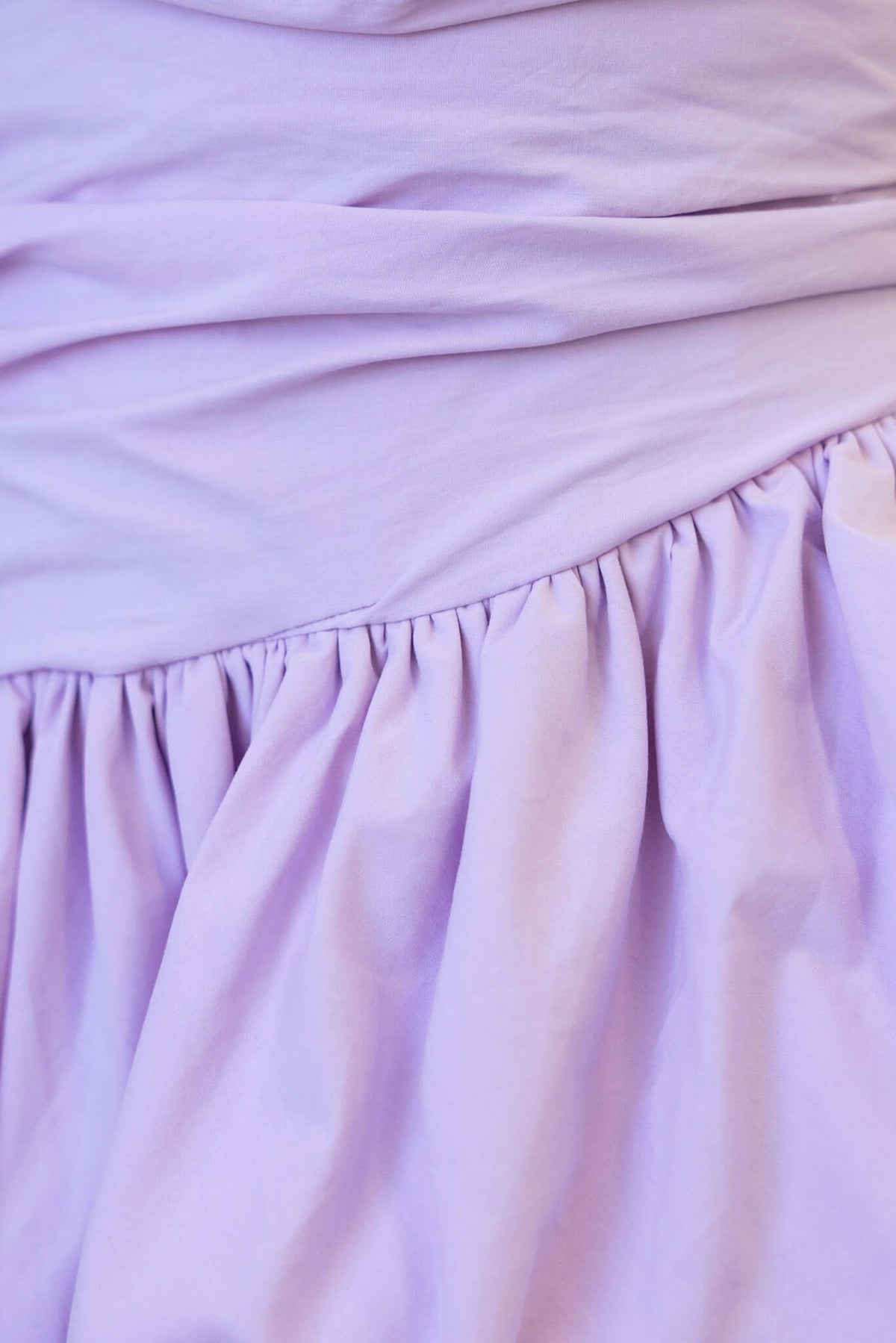 Close-up of a lilac strapless midi dress with gathered skirt, showcasing the soft fabric and elegant design details.