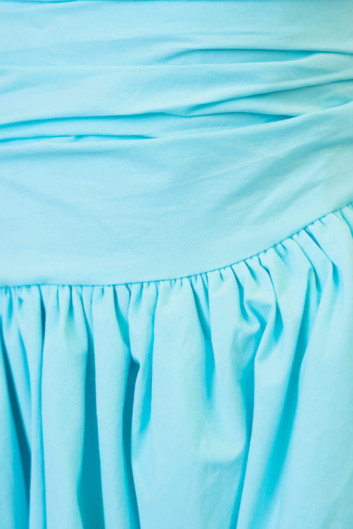 Close-up of the Carette Midi Dress showcasing the light blue fabric with gathered details and smoothing bodice.