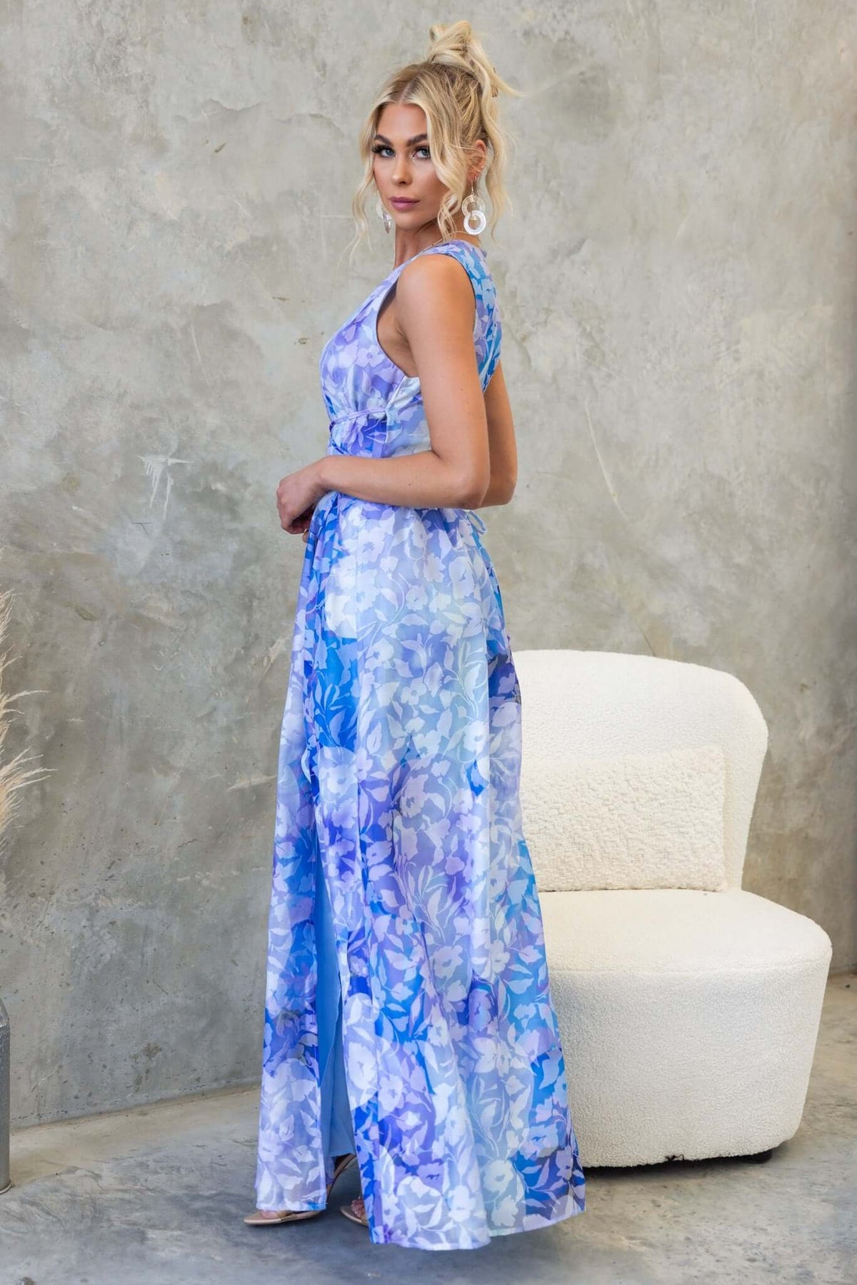 Model wearing a Kamala Maxi Dress in blue floral print, featuring a V-neckline and an asymmetric hemline.