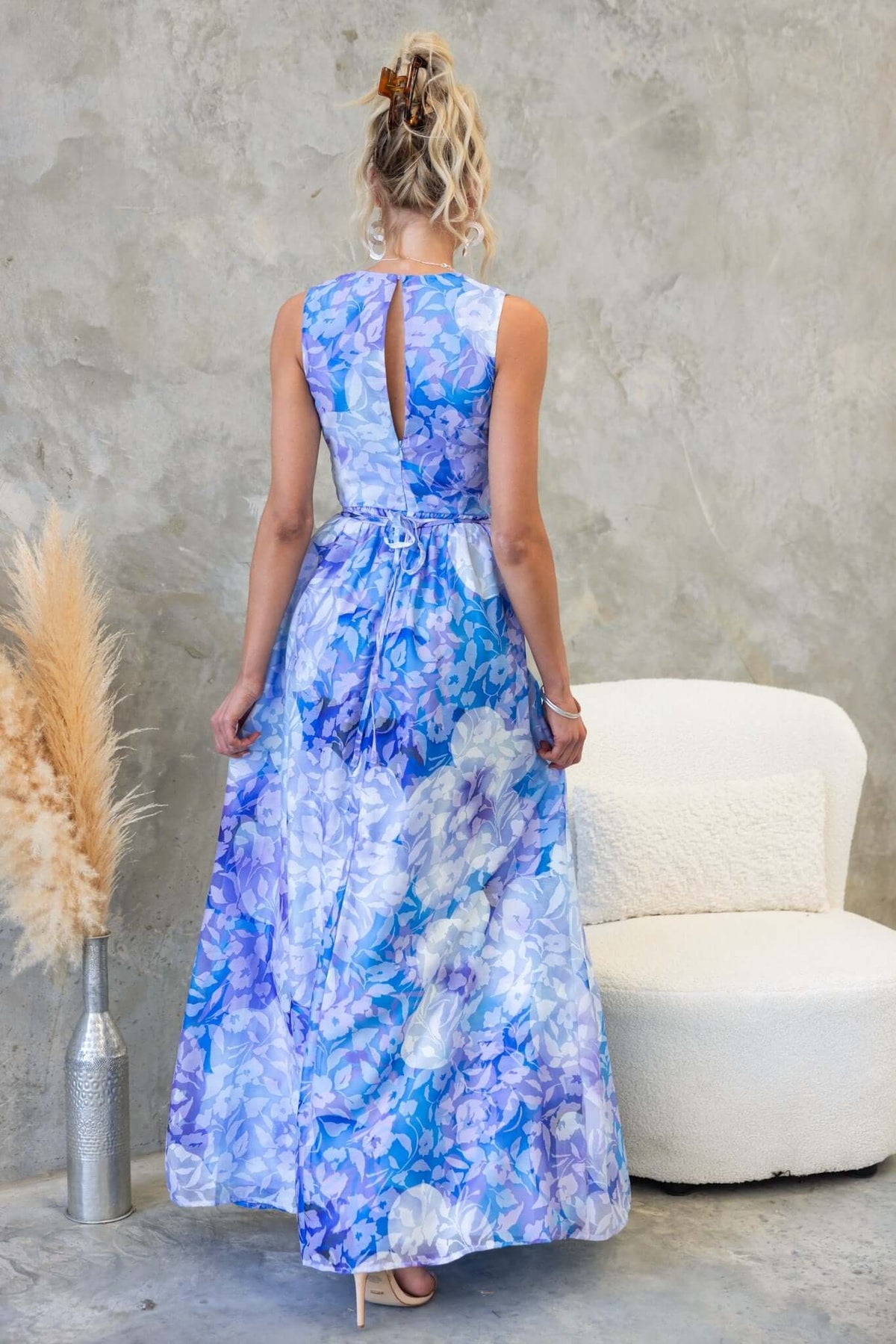 Back view of Kamala Maxi Dress in floral blue fabric, featuring a V-neckline and flowing asymmetric hemline.
