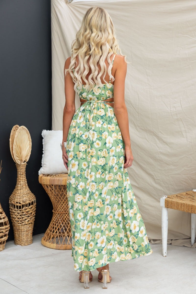 Back view of a woman in a floral print Juliette maxi dress with adjustable straps and waist tie.